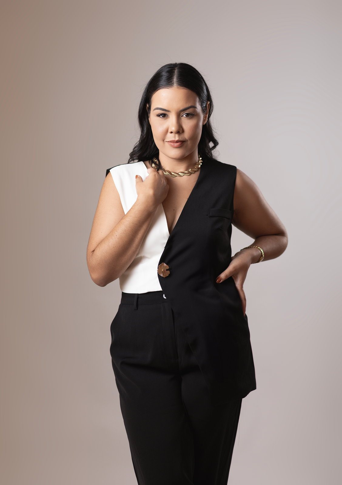 Jennedy Lima de pé, de colete preto e branco, uma das mãos na cintura, olhando para a câmera.